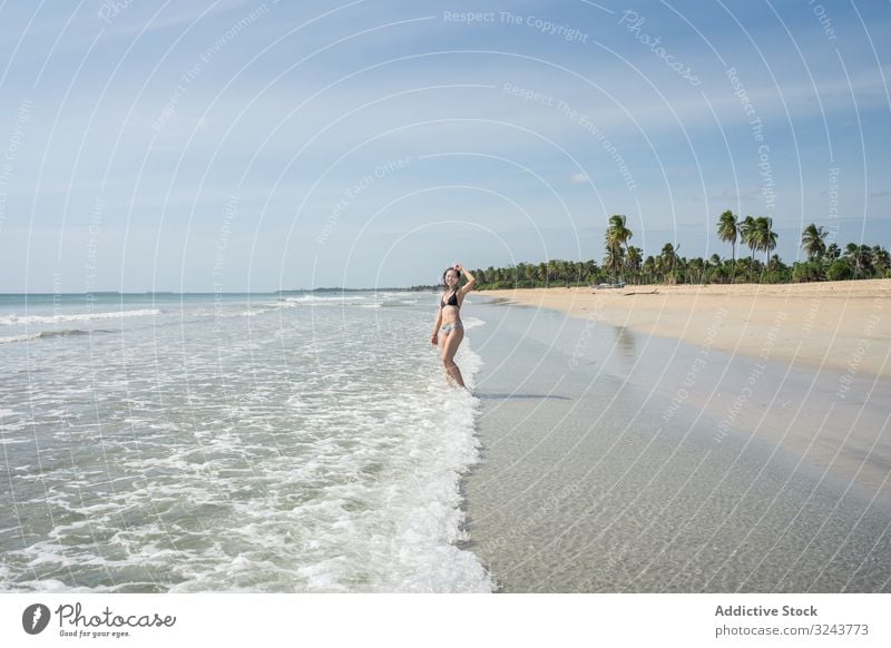 Junge Dame im Wasser am Sandstrand mit Tropenwald Strand von Mirissa Sri Lanka Wald tropisch Insel Frau Ufer Geplätscher heiter jung grün attraktiv Natur frisch