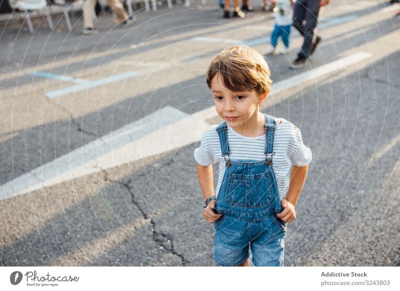 Kleiner Junge schaut auf der Straße weg Großstadt neugierig lässig wenig bezaubernd modern ruhen Hände an der Taille Asphalt urban Kind Lifestyle