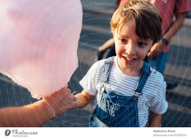 Fröhlicher Junge nimmt Zuckerwatte vom Verkäufer Jahrmarkt Anbieter aufgeregt Lächeln Straße Großstadt süß Fairness Kind Freude Glück urban Stadt verkaufen