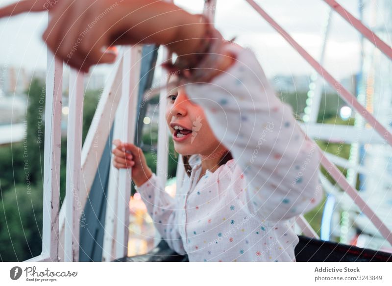 Fröhliches Mädchen fährt Riesenrad mit Eltern Mitfahrgelegenheit aufgeregt Mutter Spaß Herbst Vergnügungspark Lachen Kind Tochter Entertainment Beobachtung Höhe