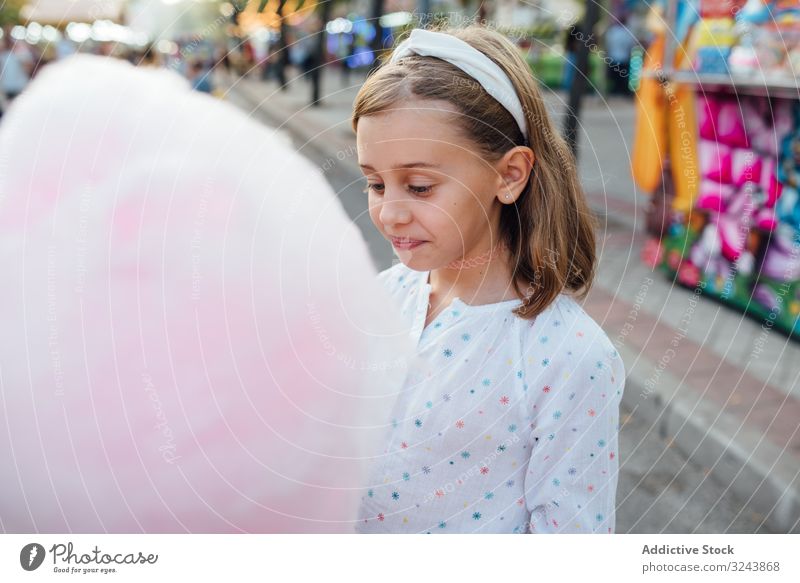 Fröhliches Mädchen isst Zuckerwatte auf der Straße Verkaufswagen essen Lächeln Großstadt Fairness Freude Kind Glück urban Stadt süß Spaß Anbieter kaufen