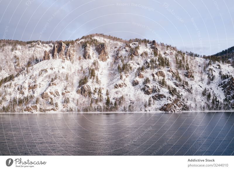 Breiter sibirischer Fluss und schneebedeckte Berge Berge u. Gebirge Winter Sibirien verschneite Landschaft Natur Felsen Hügel kalt Flussufer malerisch Russland