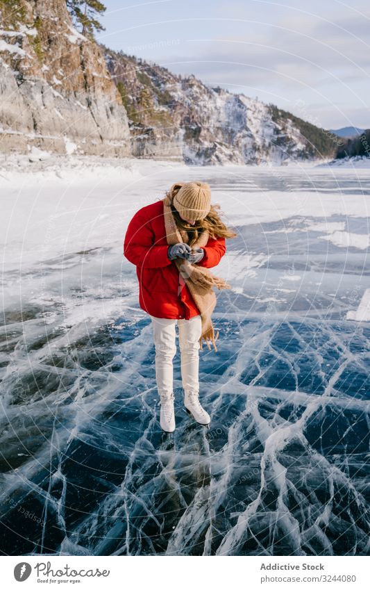 Frau in Schlittschuhen steht auf dem Eis und benutzt Telefon benutzend Schlittschuhlaufen Fluss Winter kalt Aktivität Smartphone Mobile Nachricht Anruf