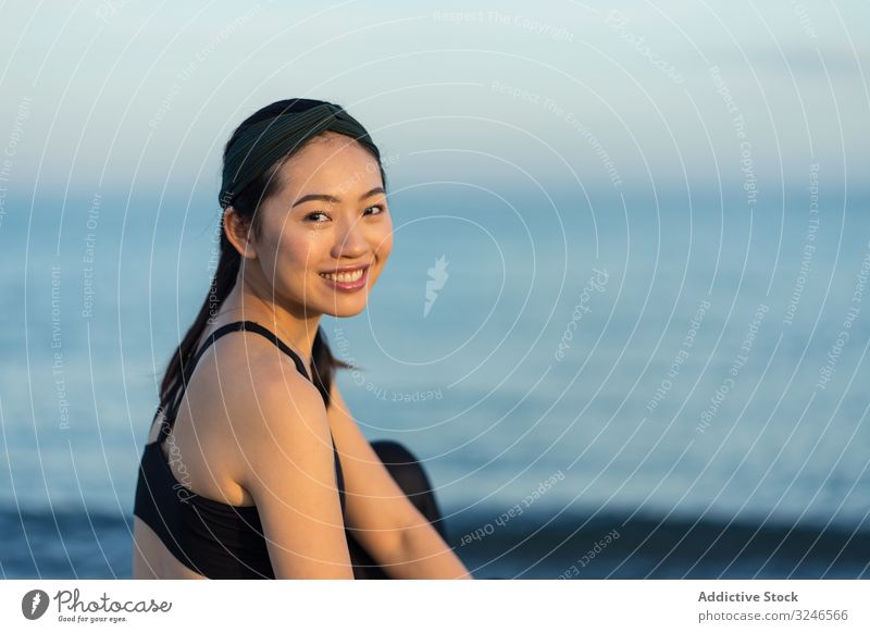 Sportliche Frau sitzt am Strand Sitzen sportlich MEER Meer sitzen jung Sportbekleidung sich[Akk] entspannen ruhen genießen asiatisch ethnisch Windstille Ruhe