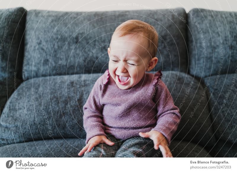 schönes kleines Mädchen, das zu Hause lacht und auf dem Sofa sitzt. Lifestyle Freude Glück Leben Freizeit & Hobby Spielen Wohnung Baby Frau Erwachsene Kindheit