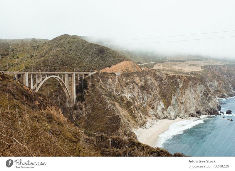 Blaue Wellen waschen felsiges Meeresufer mit Brücke bei hellem Wetter Wasser Himmel Natur MEER Landschaft Küste Strand Felsen Ufer reisen Tourismus Big Sur