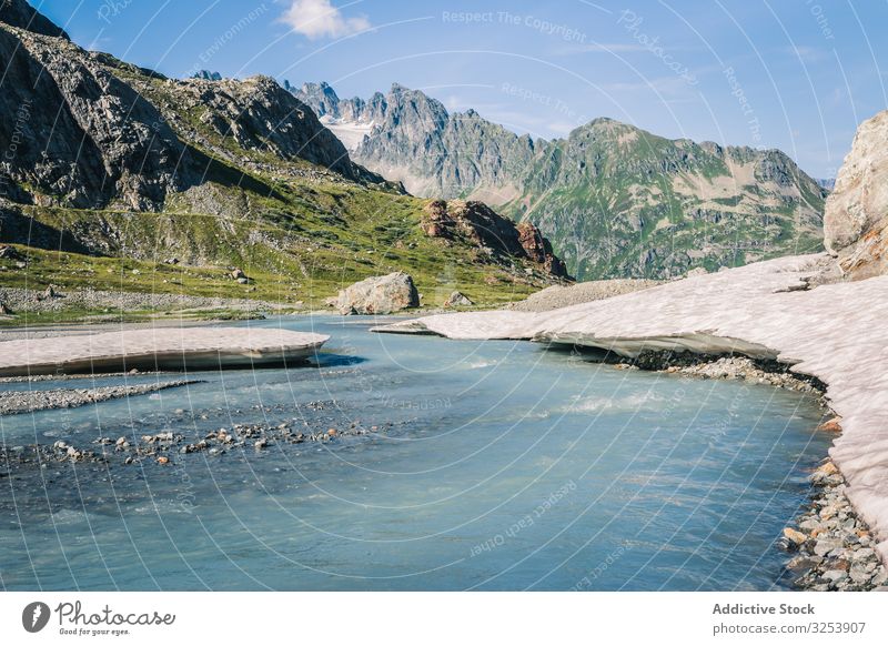 Flacher Fluss, der an felsigen Ufern an hellem Tag fließt Berge u. Gebirge fließend Wasser Natur Landschaft Himmel malerisch blau natürlich Wildnis Schnee