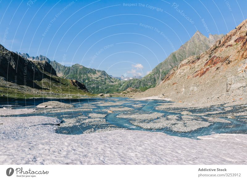 Flacher Fluss, der an felsigen Ufern an hellem Tag fließt Berge u. Gebirge fließend Wasser Natur Landschaft Himmel malerisch blau natürlich Wildnis Schnee