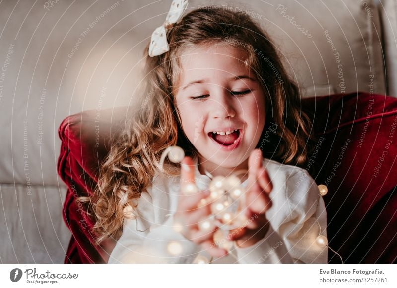 schönes Mädchen zu Hause, das mit einer Lichtergirlande spielt. Weihnachts-Konzept Weihnachten & Advent Girlande heimwärts blond blaue Augen Kind Liebe