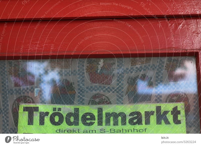 Schwarzer, dicker Schriftzug: Trödelmarkt, geschrieben auf Schild in Neon, hängt in altem Fenster, mit rotem Rahmen und nostalgischen Vorhang, hinter der Scheibe, als Werbung, Hinweis, Ankündigung, Programm für einen Flohmarkt am S-Bahnhof in der Stadt.