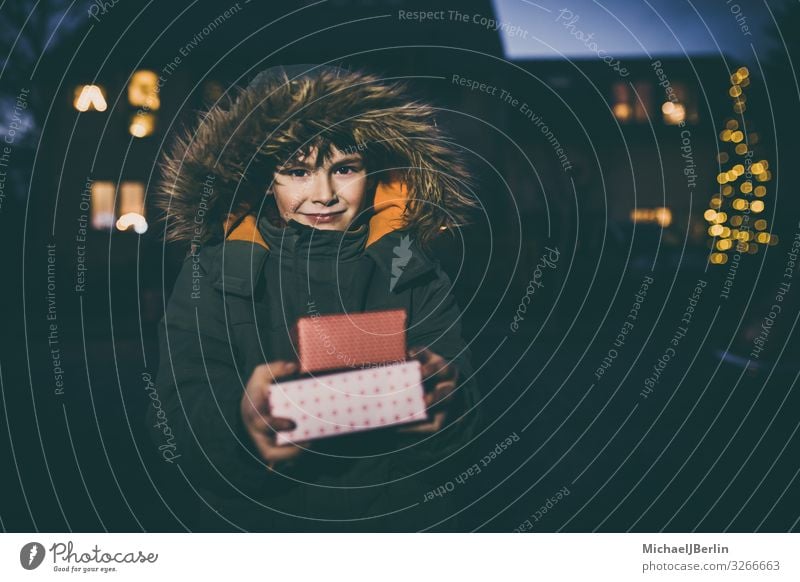 Junge mit Geschenken in Winterjacke Weihnachten & Advent Kind Mensch maskulin 1 3-8 Jahre Kindheit Freude kalt Jacke Straße Unschärfe Licht Hintergrundbild Haus