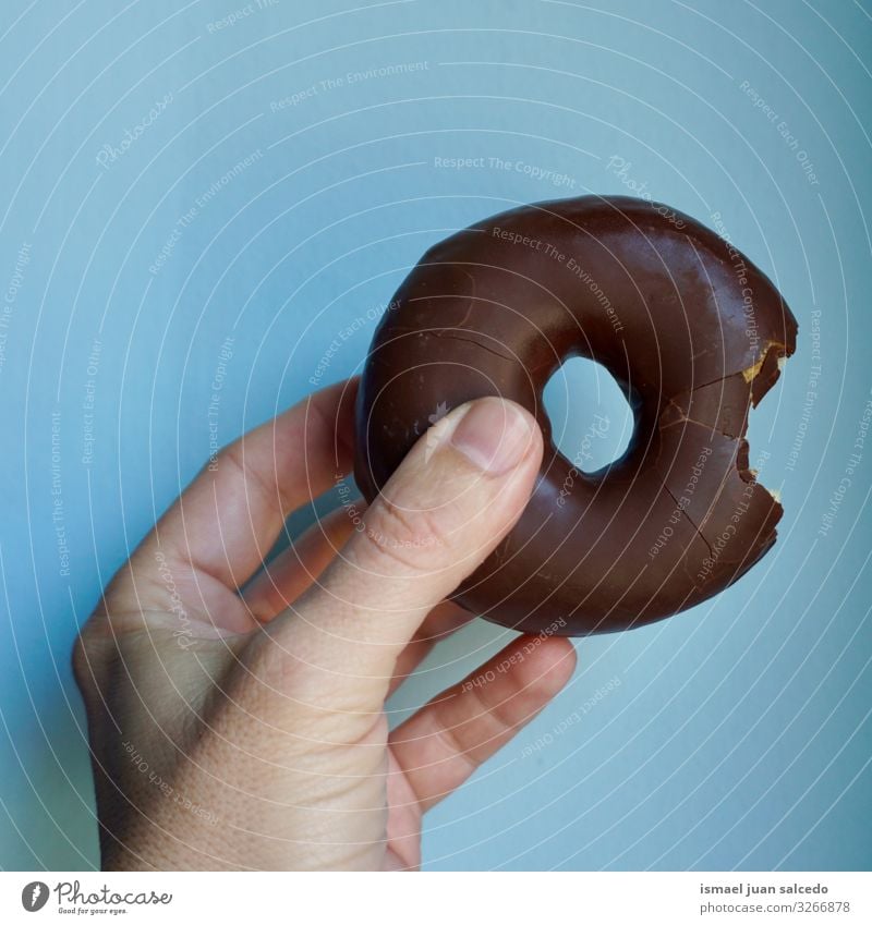 Hand mit einem leckeren Schokoladenkrapfen Krapfen Foodfotografie geschmackvoll süß Finger Körperteil blau Gebäck Gesättigte Fette Dessert Appetit & Hunger