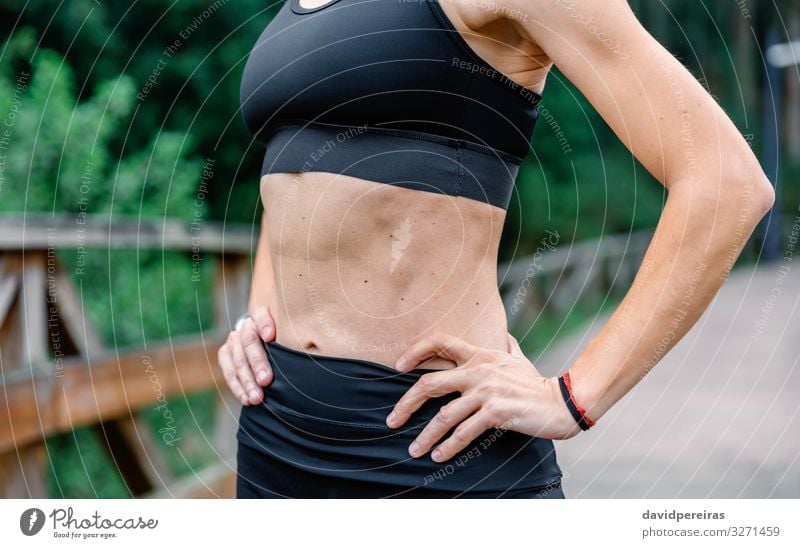 Athletin, die mit Sportbekleidung posiert. Lifestyle Mensch Frau Erwachsene Arme Hand Natur Park Fitness sportlich dünn selbstbewußt unkenntlich Bauchmuskulatur