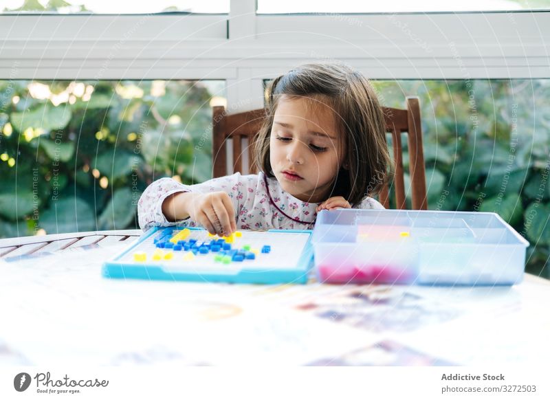 Mädchen spielt mit Mosaik-Brettspiel spielen Spiel Holzplatte kreativ fokussiert Konzentration Spielfigur farbenfroh Bildung Geduldsspiel versammeln Spaß Kind