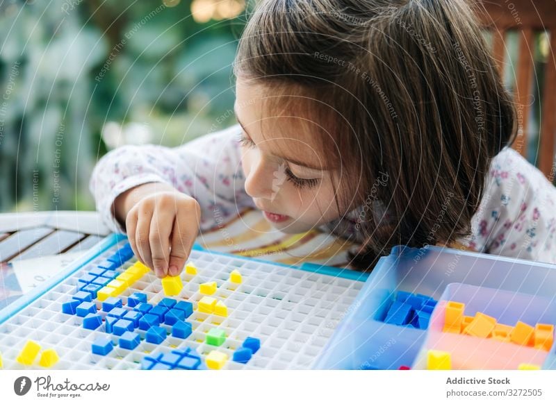 Mädchen spielt mit Mosaik-Brettspiel spielen Spiel Holzplatte kreativ fokussiert Konzentration Spielfigur farbenfroh Bildung Geduldsspiel versammeln Spaß Kind