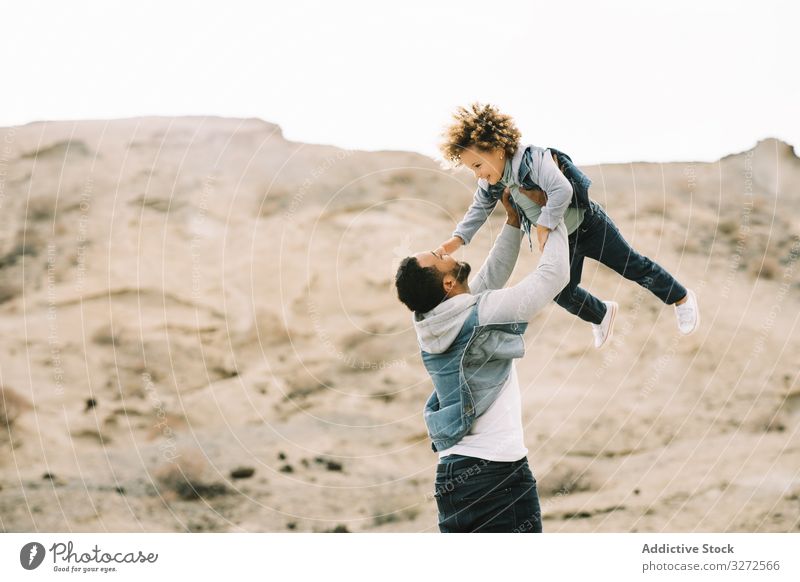 Ethnischer Vater spielt mit Kind am Boden Kleinkind spielen Spaß ruhen Sand Hügel Lächeln Eltern Glück heiter Lifestyle modern Natur Papa Mann horizontal Bonden