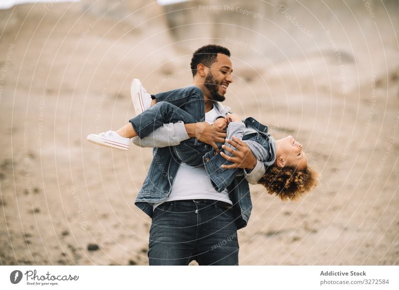 Ethnischer Vater spielt mit Kind am Boden Kleinkind spielen Spaß ruhen Sand Hügel Lächeln Eltern Glück heiter Lifestyle modern Natur Papa Mann horizontal Bonden