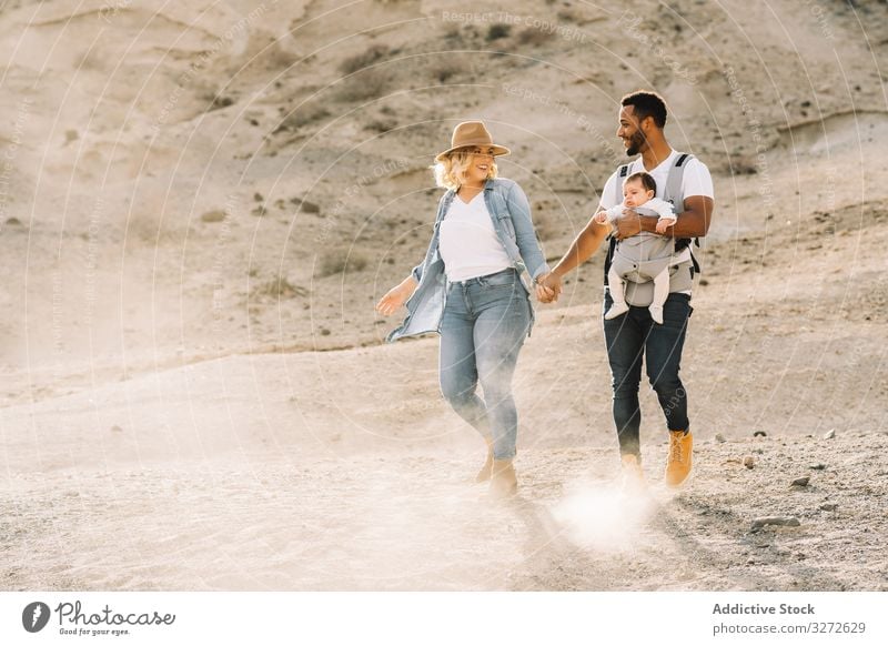 Verschiedene Eltern tanzen beim Laufen mit Baby Tanzen Familie Glück Lächeln Sand wüst Spaziergang führen Spaß Natur neugeboren heiter Lifestyle modern Kind