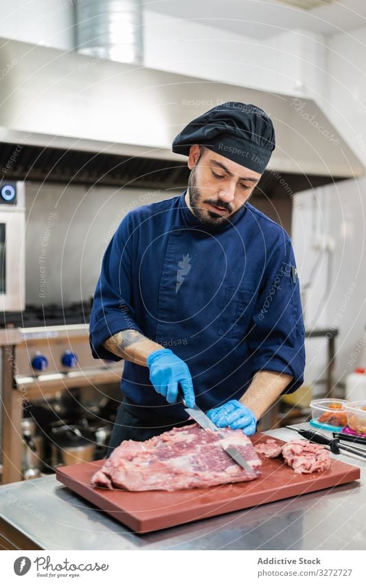 Chefkoch schneidet Fleisch in der Küche Küchenchef geschnitten Scheibe roh Mann vorbereiten Koch professionell Schneidebrett Messer Tisch Beruf männlich