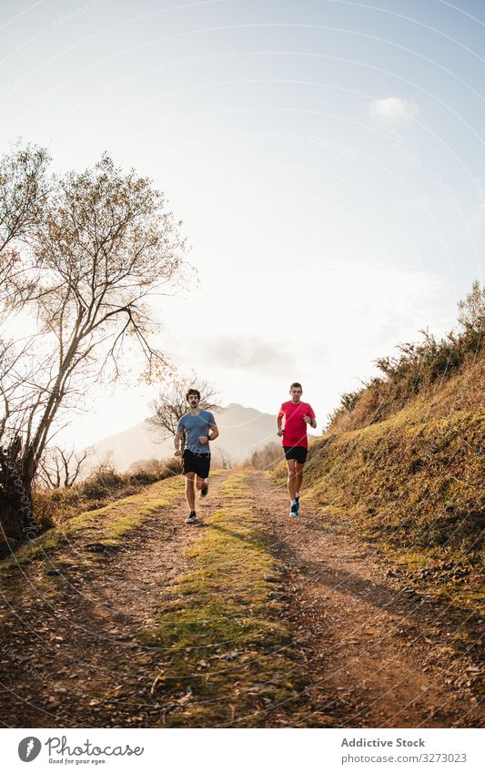 Sportliche Männer laufen in den Bergen Berge u. Gebirge sportlich aktiv Jogger Natur Straße Sportler Inspiration Zusammensein Morgen Freiheit Training Nachlauf