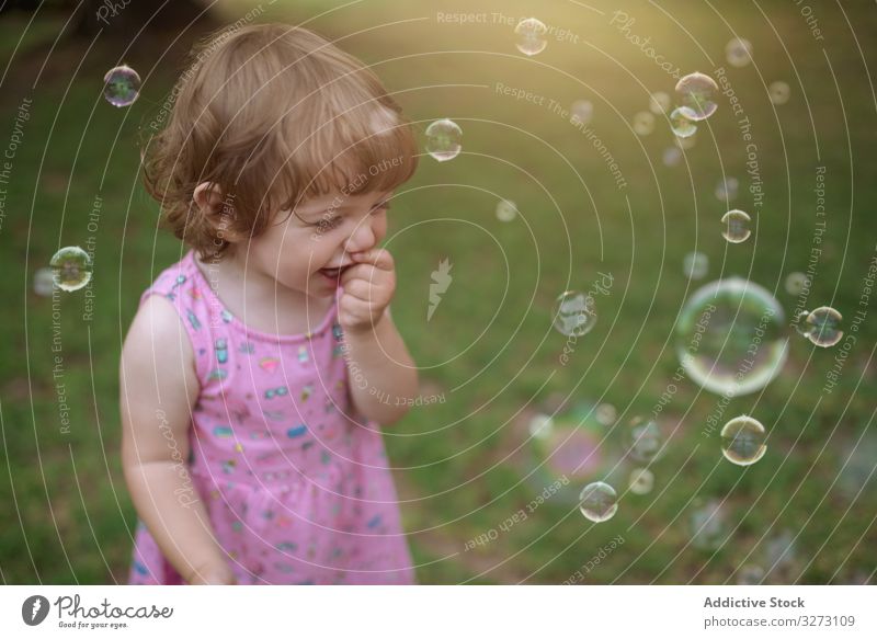 Fröhliches Mädchen spielt mit bunten Blasen im Gras Seife Kindheit freudig Spaß bezaubernd Spielen heiter Park spielerisch Genuss Aktion nass wenig Bewegung