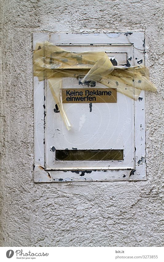 Schriftzug auf Schild: Keine Reklame einwerfen, hängt an altem, kaputten, weissen Briefkasten aus Blech, an der Wand vom Haus. Der Kasten ist mit Paketband, Tesa, Kreppband zugeklebt, verschlossen als Hinweis auf Verbot, Umzug des Mieters, Leerstand.