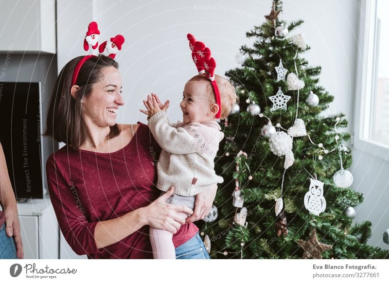 Mutter und süßes Mädchen spielen zu Hause mit dem Rentierdiadem. Weihnachts-Konzept Spielen Diadem Weihnachtsmann Mutterschaft Glück niedlich Baby ein Jahr