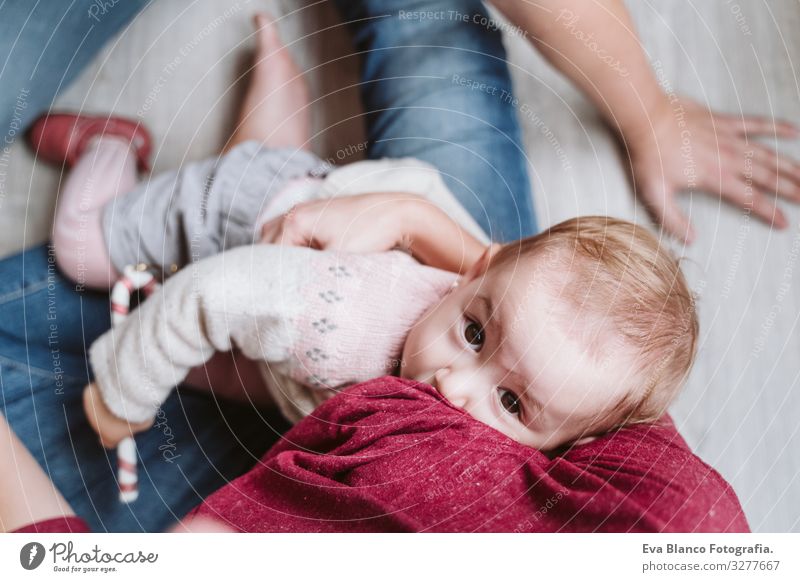 Mutter, die ihr Kind am Weihnachtsbaum stillt stillen Fressen Essen natürlich Lebensmittel Mutterschaft Glück niedlich Baby Mädchen ein Jahr dekorierend