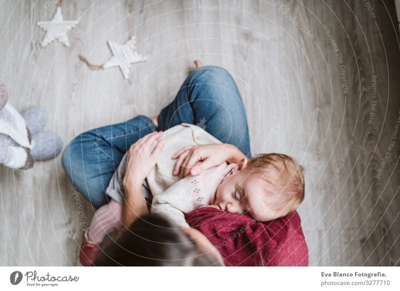 Mutter, die ihr Kind am Weihnachtsbaum stillt stillen Fressen Essen natürlich Lebensmittel Mutterschaft Glück niedlich Baby Mädchen ein Jahr dekorierend