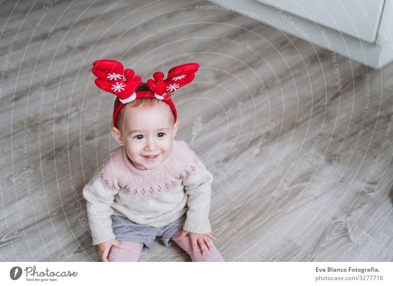 ein fröhliches Mädchen, das zu Hause mit dem Rentierdiadem spielt. Weihnachts-Konzept Spielen Diadem Weihnachtsmann Mutter Mutterschaft Glück niedlich Baby