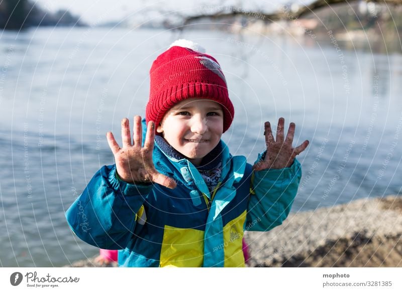 Junge mit schmutzigen Fingern am Wasser Natur bunt draußen dreck dreckig erlebnis finger hand hände jacke junge kalt kind mütze natürlich rhein rot spielen ufer