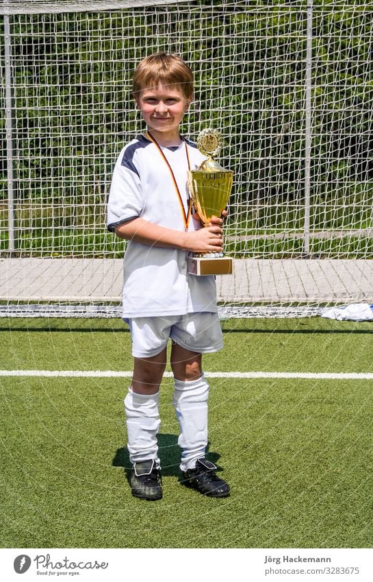 der Junge hält nach dem Spiel stolz den Pokal in der Hand Freude Glück Spielen Club Disco Sport Fußball Kind Freundschaft Kindheit Jugendliche Bewegung Fitness