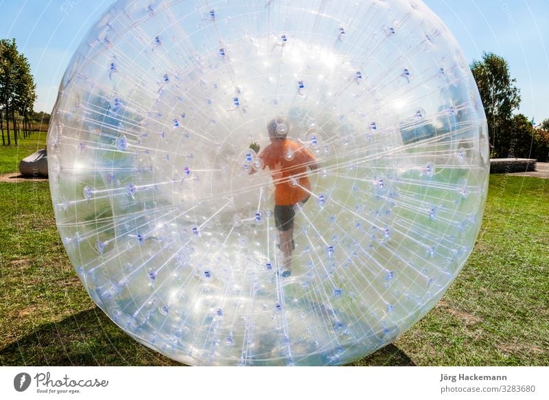 Kinder haben Spaß im Zorbing-Ball Freude Glück Freizeit & Hobby Abenteuer Sommer Sonne Sport Gras Wiese Hügel Kugel Tropfen Bewegung Fitness lachen