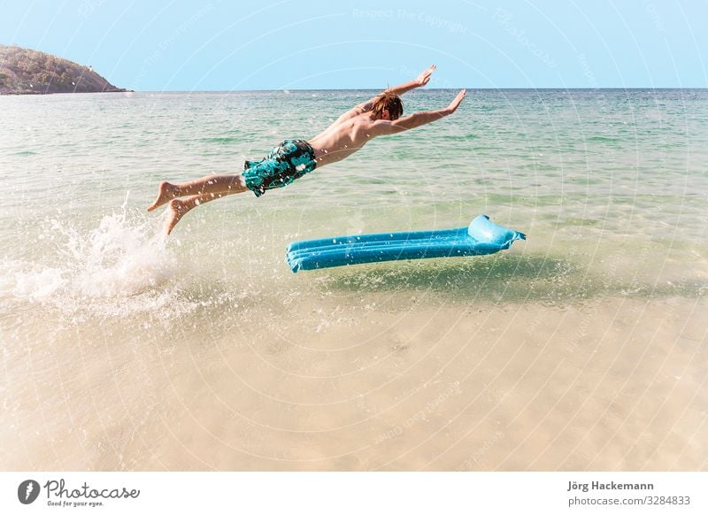 Junge mit roten Haaren genießt es, auf der Luftmatratze zu springen Freude Ferien & Urlaub & Reisen Strand Meer Insel Wellen Jugendliche Himmel niedlich