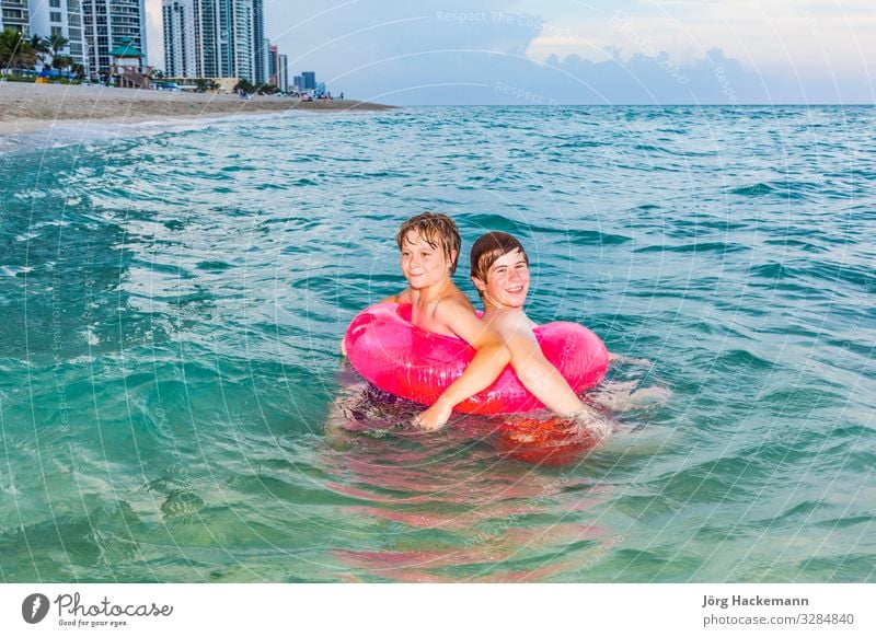 Brüder in einem Schwimmring haben Spaß im Meer Freude Glück schön Haut Erholung Freizeit & Hobby Ferien & Urlaub & Reisen Sonne Wellen Kind Junge Jugendliche