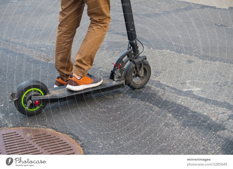 Roller mit Luftreifen asphaltierter Gullydeckel braune Hose Mann Erwachsene 13-18 Jahre Jugendliche 18-30 Jahre 30-45 Jahre Straße Tretroller Turnschuh Spielen