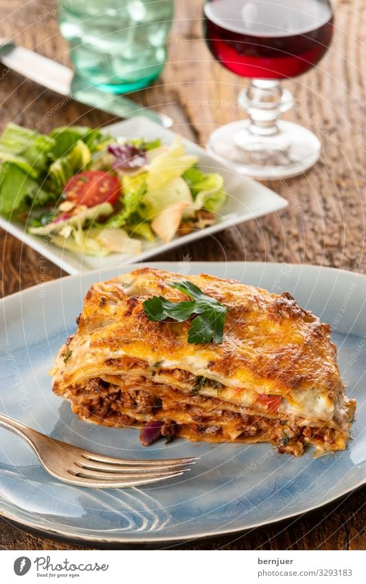 Lasagne auf einem Teller Fleisch Käse Gemüse Ernährung Abendessen Geschirr Gabel Gastronomie Holz frisch lecker Petersilie Pasta geschmackvoll Platte