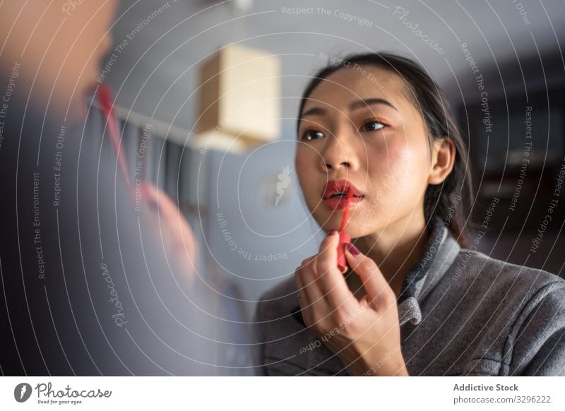 Junge Frau trägt Lippenstift vor dem Spiegel auf Make-up Kosmetik lässig bewerben Schönheit jung Reflexion & Spiegelung Gesicht Mode Pflege Teint