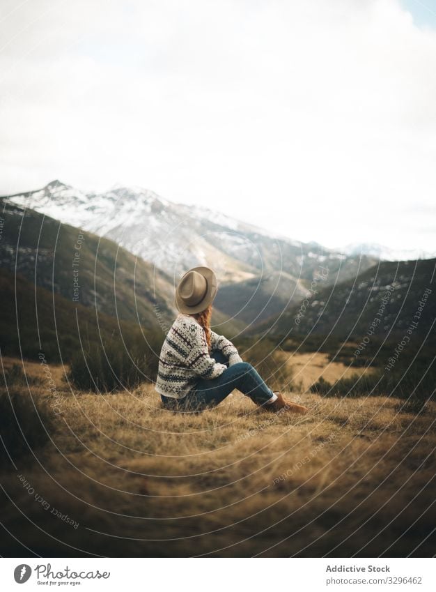 Rothaarige Frau, die nachdenklich auf einer Wiese in den Bergen sitzt gemütlich Berge u. Gebirge Landschaft besinnlich warm Pullover bequem Mode Komfort