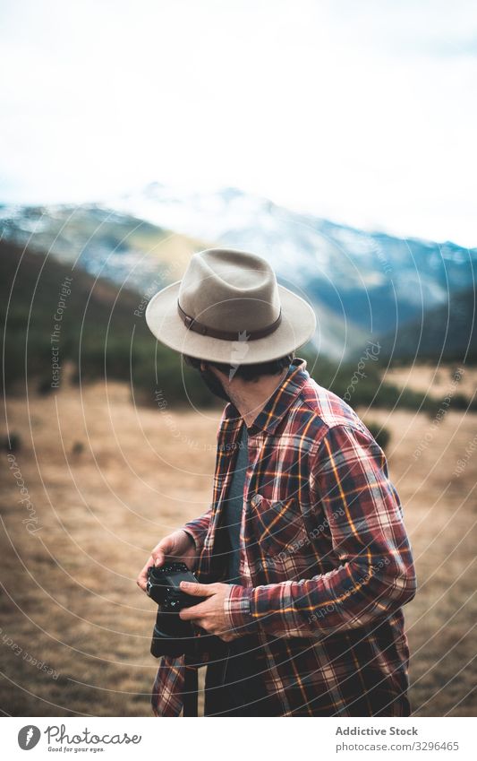 Mann mit Kamera in der Hand blickt zurück auf Berge Reisender Fotokamera Berge u. Gebirge Hut reisen Fotograf Natur Abenteuer Tourist Urlaub Fotografie Freiheit