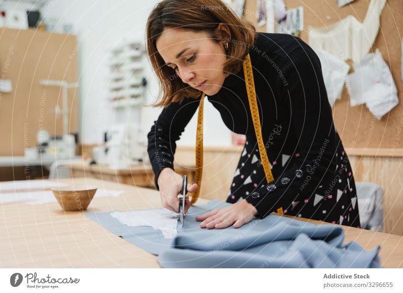 Schneiderin schneidet Tuch auf dem Tisch Damenschneiderin geschnitten Gewebe Detailaufnahme Frau Schere Arbeit Werkstatt Mode Bekleidung Textil Designer