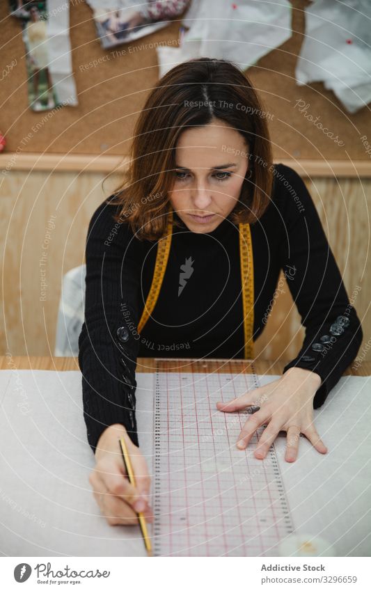 Schneiderinnen-Zeichnungsausschnitt in der Werkstatt zeichnen Ausschnitt Frau Tisch fokussiert Arbeit Erwachsener Designer Arbeitsplatz professionell