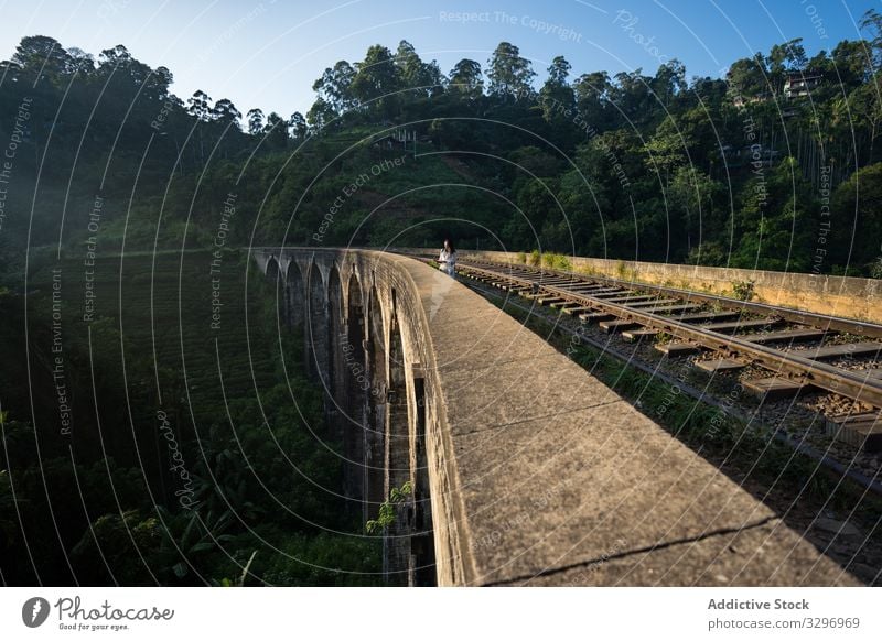 Nachdenkliche Asiatin geht in alter altertümlicher Brücke entlang der Eisenbahn Sri Lanka Frau grün Wald nachdenklich antik asiatisch Brücke mit neun Bögen