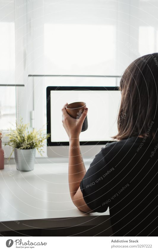 Anonyme Frau, die am Arbeitsplatz mit einem Smartphone fotografiert fotografierend Bild Arbeitsbereich Funktelefon Büro Computer benutzend Tasse teilen