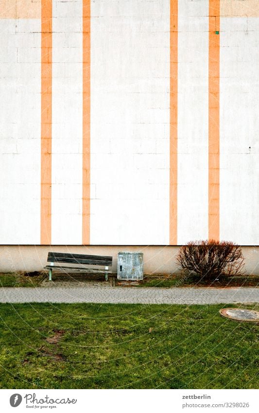 Fassade mit Streifen Haus Mehrfamilienhaus Wohnhaus Plattenbau wbs 70 Neubausiedlung Wand Mauer Bank Menschenleer Textfreiraum trist Traurigkeit Einsamkeit