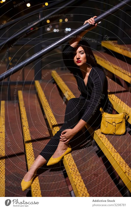 Frau in stilvollem Outfit im Treppenhaus modisch trendy Abenddämmerung Schatten stylisch Bekleidung Großstadt Straße Stehen jung Verschlussdeckel Dame brünett