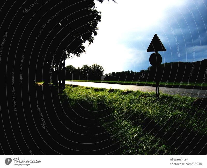 Unwetter droht Waldrand dunkel Verkehrsschild Wolken bedrohlich Wiese grün glänzend Straße Srtaßenrand hell Himmel blau Sonne