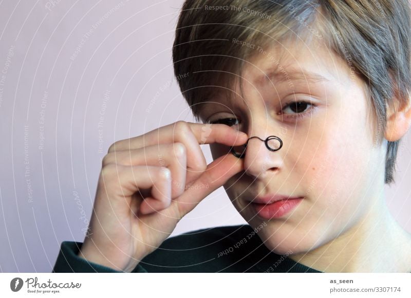 Junge blickt mit skeptischem Blick durch kleine Brille Monokel Blick in die Kamera Porträt Mensch maskulin Gesicht blond Jugendliche 13-18 Jahre intelligent