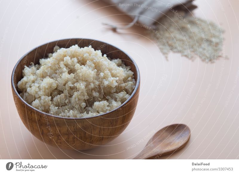 gekochte Quinoa in Schale und Holzlöffel auf braunem Grund Schalen & Schüsseln Löffel Kochlöffel Diät kochen & garen brauner Hintergrund Müsli Protein roh Samen