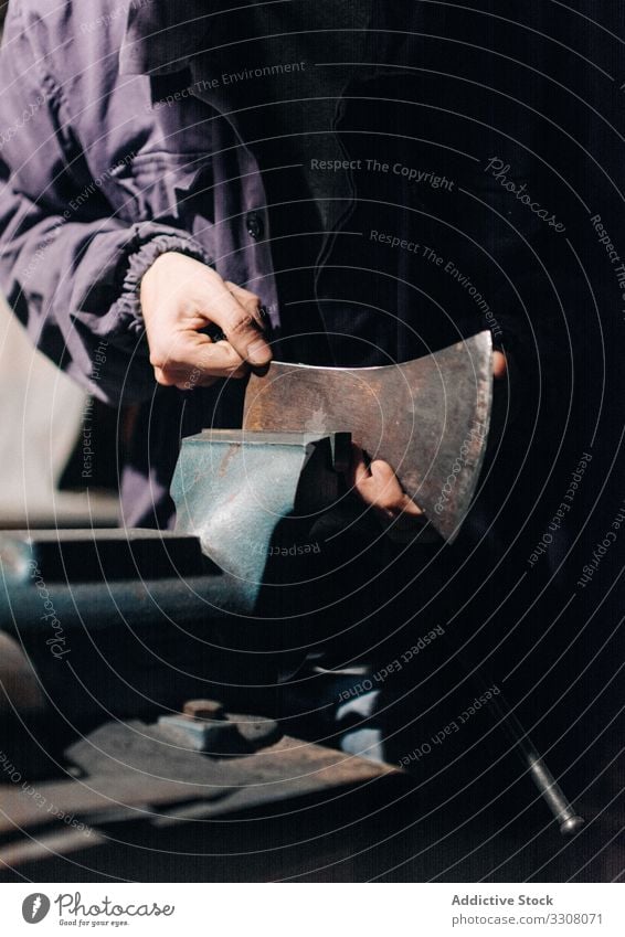 Getreidehandwerker prüft Axt in der Werkstatt Mann Klinge Schleifmaschine prüfen schärfen benutzend Arbeit Werkzeug Handwerk männlich Metallbearbeitung